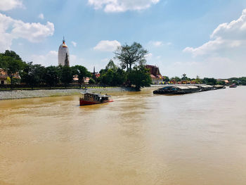 View of boats in river against cloudy sky