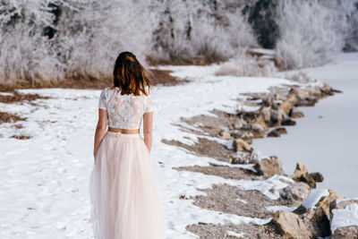 Rear view of woman standing on snow covered land