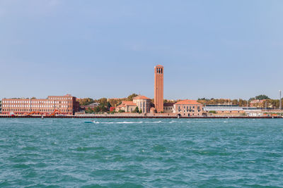 Sea by buildings against clear blue sky