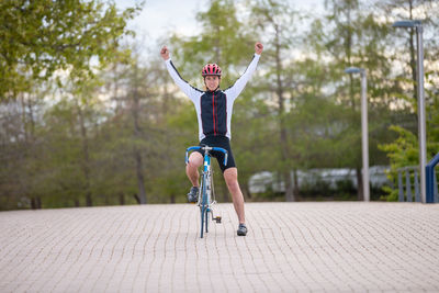 Portrait of smiling man with arms raised sitting on bicycle at road