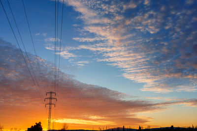 Low angle view of silhouette electricity pylon against romantic sky