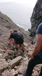 Rear view of man and woman on rock at sea shore