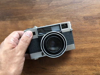 Close-up of hand holding camera on wooden table