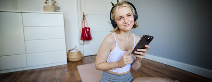 Portrait of young woman drinking wine in gym