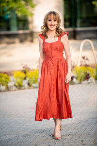 Full length portrait of young woman wearing red dress in plaza