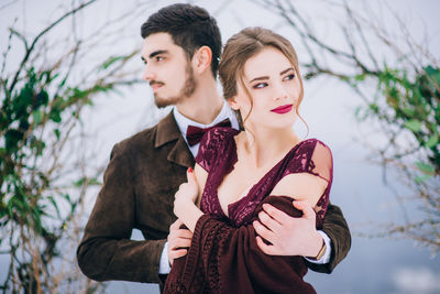 Portrait of young couple standing against trees