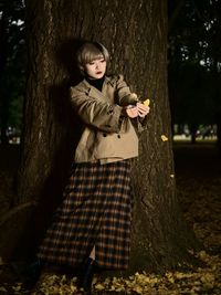 Woman standing by tree trunk