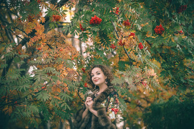 Young woman standing against tree