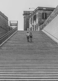 Rear view of people walking on staircase of building