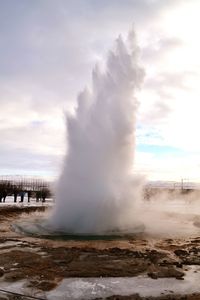 Waves splashing on shore against sky