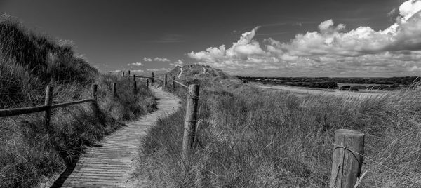 Footpath amidst field against sky