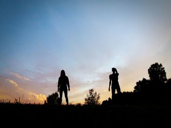 Silhouette men on field against sky during sunset