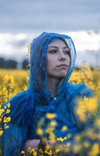 Thoughtful young woman wearing raincoat amidst flowers