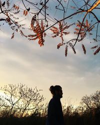 Woman standing by tree against sky during sunset