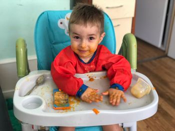 Portrait of cute boy with messy face sitting on high chair