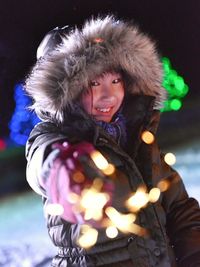 Portrait of girl in wearing fur hat holding sparkler at night