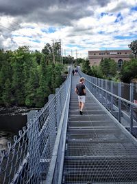 People walking on road against cloudy sky