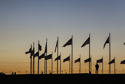 Silhouette flags against clear sky during sunset