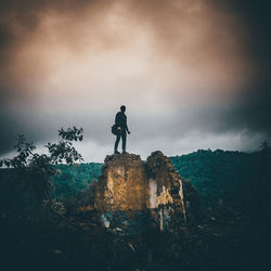 Man standing on rock against sky