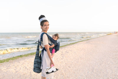 Happy mother with daughter on beach against sky