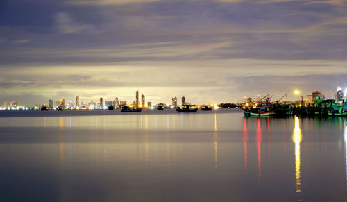 Scenic view of river by illuminated buildings against sky