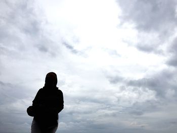 Low angle view of silhouette woman standing against sky