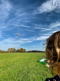 Woman flying over field against sky