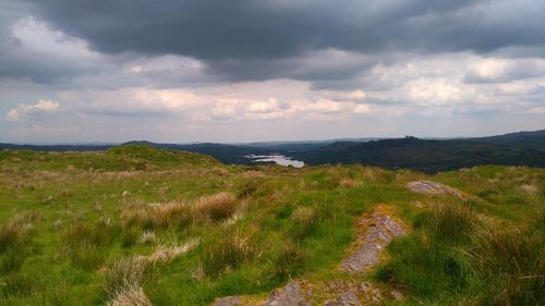 Scenic view of grassy landscape against cloudy sky