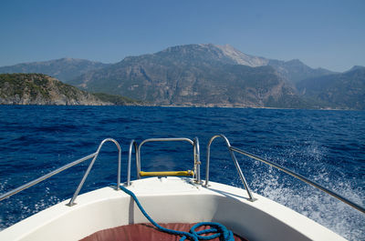 Sailboat sailing in sea against mountains