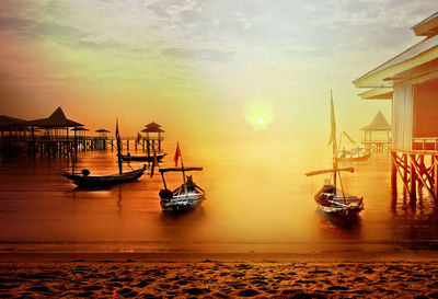 Sailboats moored on sea against sky during sunset