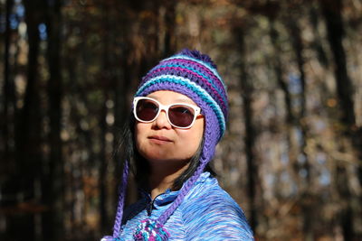 Portrait of woman wearing sunglasses against trees in forest