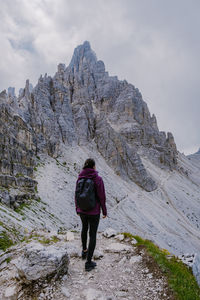 Rear view of man standing on rock against sky