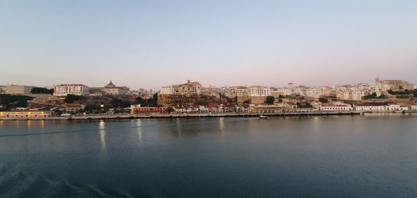 River by buildings in city against clear sky