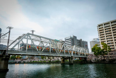 Bridge over river in city against sky