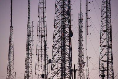 Low angle view of electricity pylon against sky during sunset