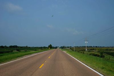 Road amidst field against sky