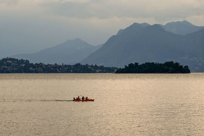 Tourists kayaking on lake maggiore at sunset, italy