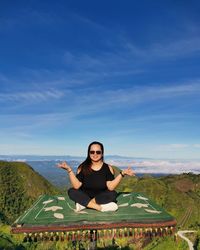 Portrait of young woman sitting against blue sky