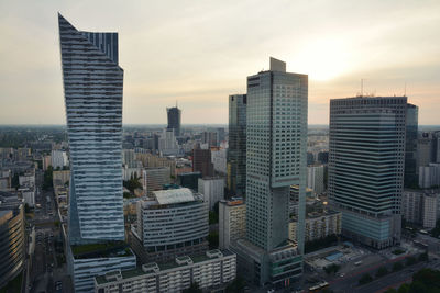 Modern buildings in city against sky during sunset