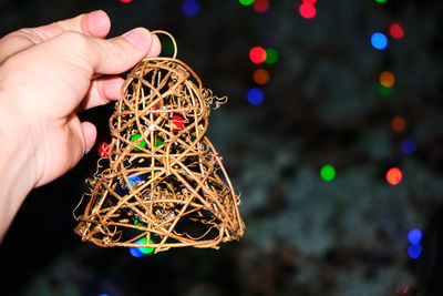 A handmade bell made of wicker, held by a hand of a you