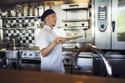 Female chef serving food in kitchen at restaurant