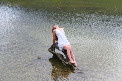 Woman lying on driftwood at lake