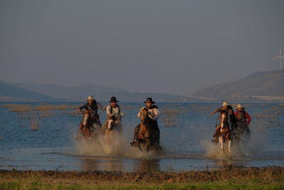 People enjoying in water against clear sky