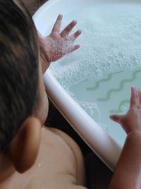 High angle view of boy by soap sud in bathtub