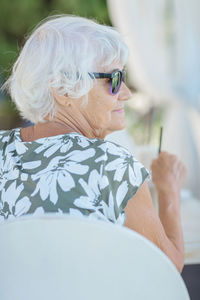 Attractive senior woman sitting in a summer outdoor cafe