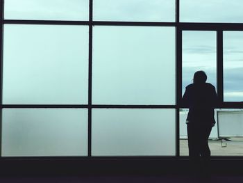 Rear view of man standing by window