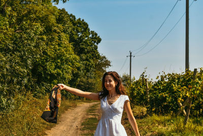 Happy young woman with arms raised against sky