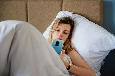 Caucasian woman relaxing in bed and use smartphone, online communication and social media concept