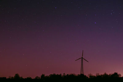 Low angle view of wind turbines against sky at night