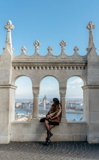 Girl sitting in arched window at fisherman's bastion in budapest, hungary